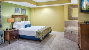 Une chambre d’hôtel comprenant un lit, une table de chevet, une lampe et une salle de bain avec une baignoire et un lavabo.