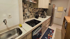 A modern kitchen with a gas stove, stainless steel sink, and a built-in oven. - Apto 2 Quartos com 1 Suíte a Poucos Passos da Praia (Vila Velha)