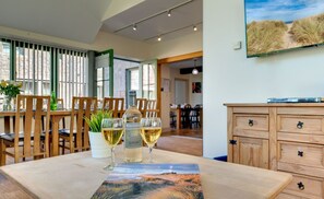 A dining area with a table set for two, featuring a bottle of wine and glasses.