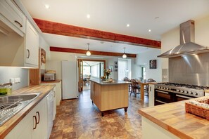 A spacious kitchen with a central island, wooden flooring, and a modern stove.