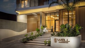 A modern building with a well sign, a staircase, and a reception area. - Well Residences - By AVA Rentals (Asunción)