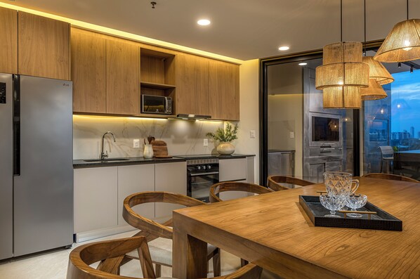 Eine moderne Küche mit Holzschränken, Edelstahlgeräten und einem Essbereich mit Holztisch und -stühlen.