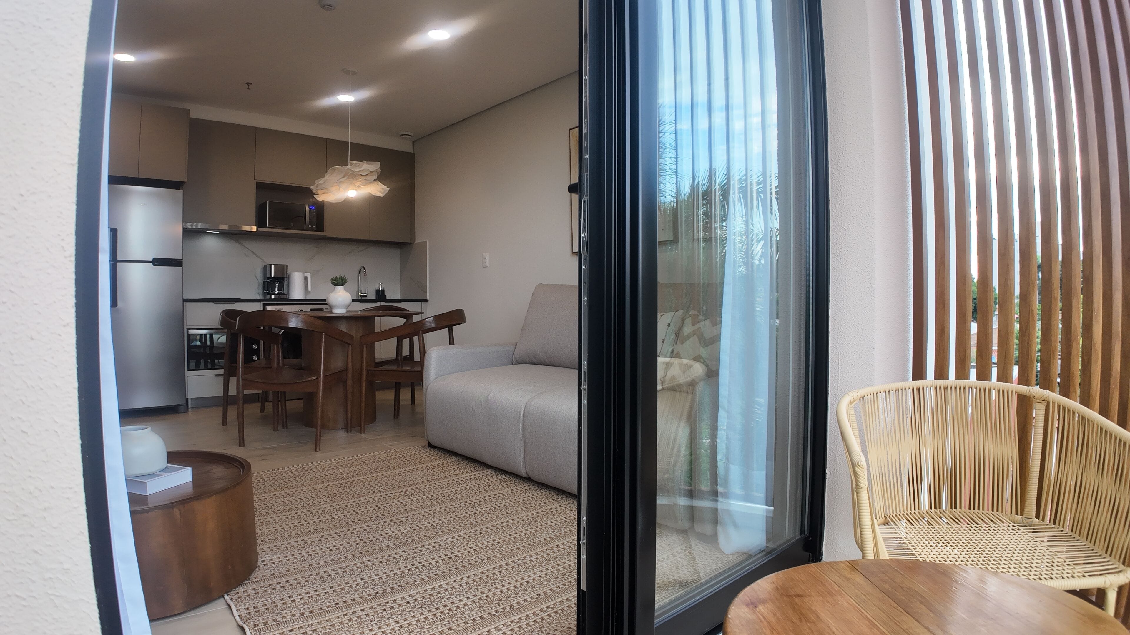 Un apartamento moderno con cocina, comedor y un balcón con una silla de mimbre.