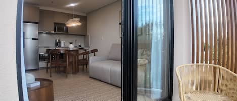 Un apartamento moderno con cocina, comedor y un balcón con una silla de mimbre.