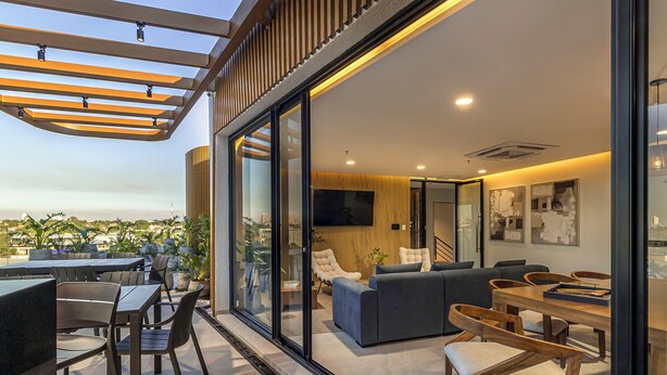An outdoor patio with tables and chairs, a sofa, and a TV screen. - Well Residences - By AVA Rentals (Asunción)