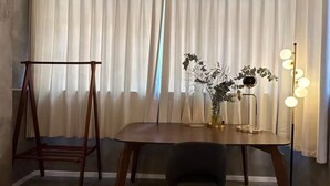 Ein Essbereich mit Holztisch, Stuhl, einer kleinen Pflanze und einer Stehlampe.