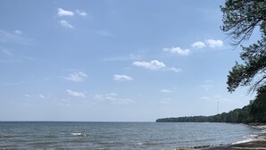 Ein felsiger Strand mit Wellen, einem klaren Himmel und weiter Küste im Hintergrund.
