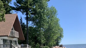 Ein Haus mit Terrasse und Rasenfläche an einer felsigen Küstenlinie.