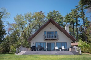 Une maison à deux étages avec un balcon, une véranda à l’avant avec des marches et une cheminée.