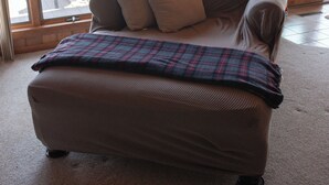 Ein Wohnzimmer mit einer Couch, einer Karo-Decke und einer Tischlampe.
