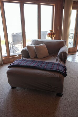 A living room with a sofa, a plaid throw blanket, and a table lamp.