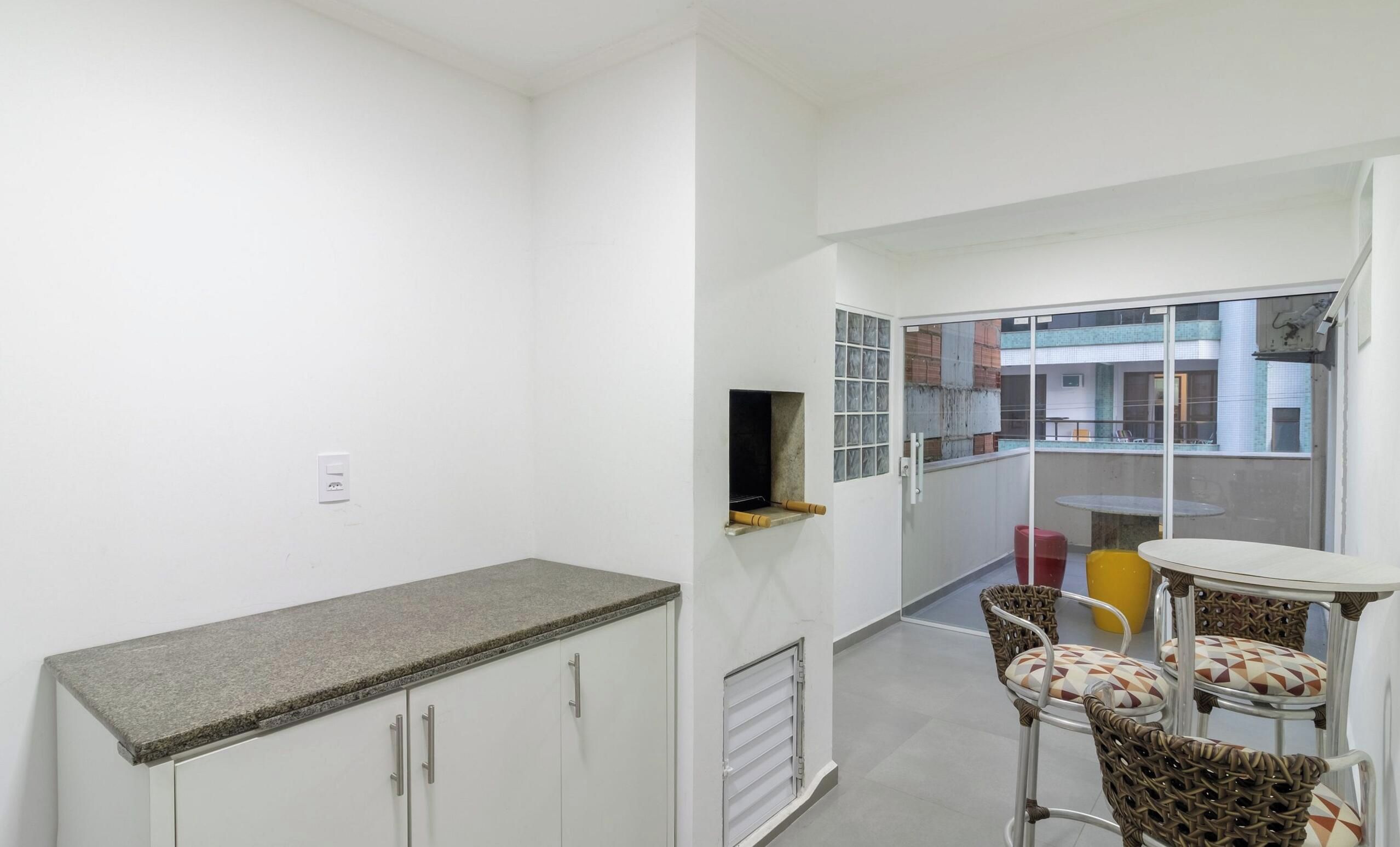 A small kitchenette with a countertop and cabinets, a sliding glass door leading to an outdoor area with a table and chairs.