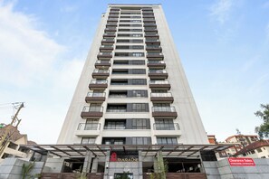 A tall, modern building with multiple balconies and a clear sky. - Luxurious apartment near mall and Carrefour, giving a cozy and homely vibe (Nairobi)