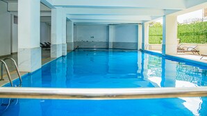 Une piscine intérieure à l’eau claire, dotée d’un plongeoir et bordée de chaises longues.