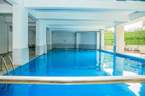 An indoor swimming pool with clear water, a diving board, and lounge chairs by the poolside. - Luxurious apartment near mall and Carrefour, giving a cozy and homely vibe (Nairobi)
