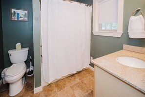 Un baño con inodoro, cortina de ducha, lavamanos y espejo.