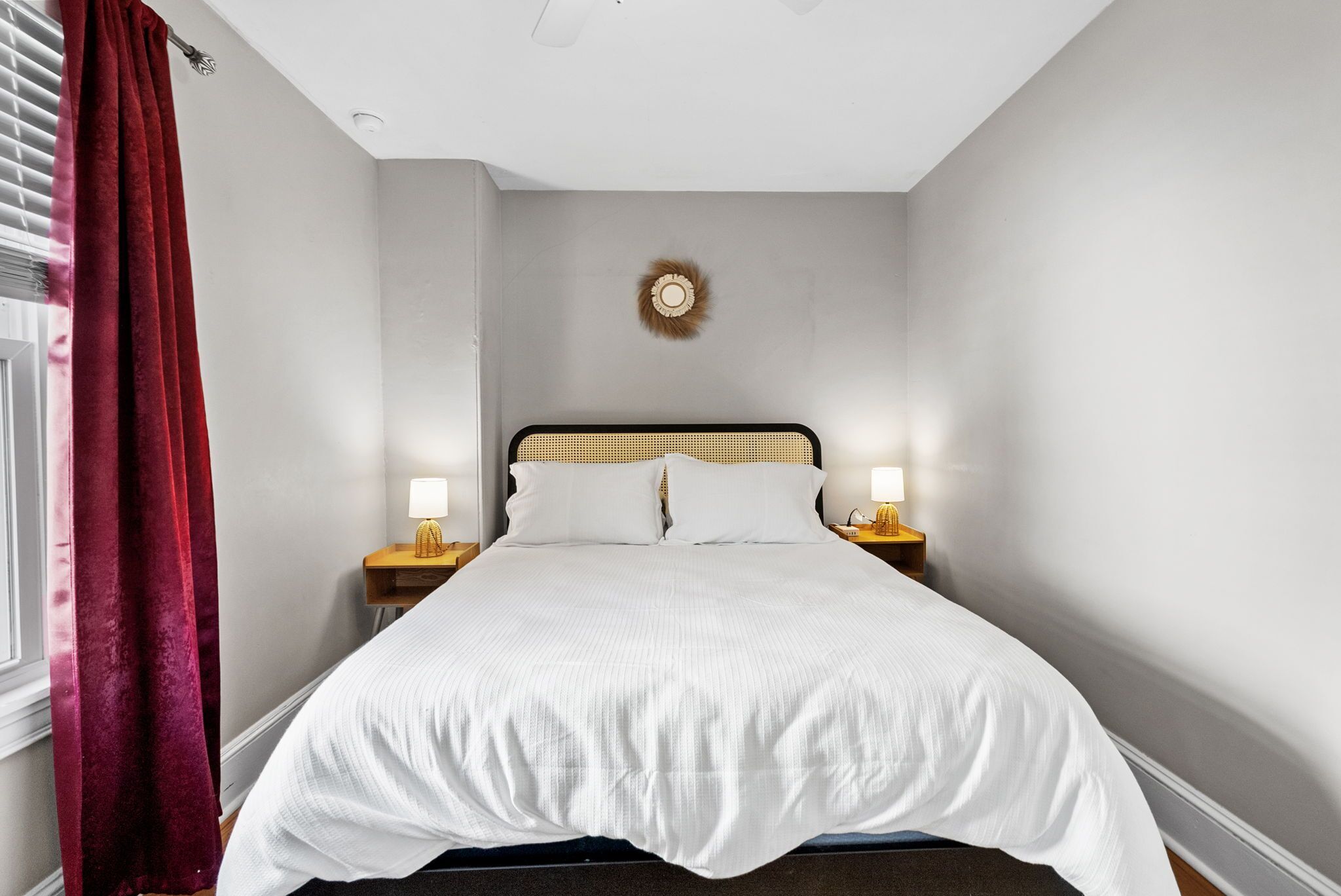 A neatly made bed with white bedding, a wooden headboard, and two bedside lamps.