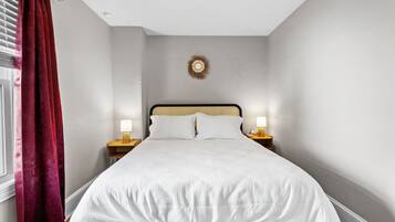 A neatly made bed with white bedding, a wooden headboard, and two bedside lamps.