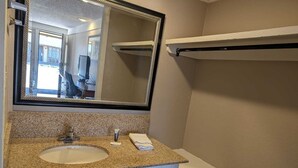 A bathroom with a granite countertop sink, a mirror, a towel rack, and a white vanity. - Exceed Inn Indianapolis Airport South (Indianapolis)