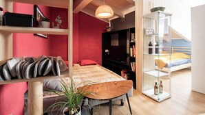 Un dormitorio moderno con una cama de madera, una pared de acento roja, una estantería y un aparador de vidrio.