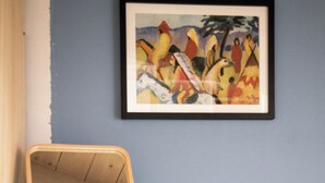 Una mesa de comedor con una silla de madera, un cuadro enmarcado en la pared y un mueble de madera.