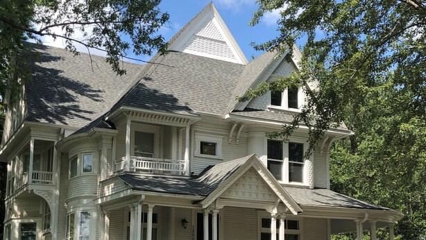 A large, two-story house with a wrap-around porch, multiple windows, and a steeply pitched roof. - The Fannie Historic Apartment (Eau Claire)