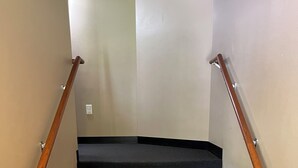 A staircase with wooden handrails and dark carpeted steps. - The Fannie Historic Apartment (Eau Claire)