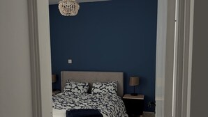 Une chambre à coucher avec un lit, une table de chevet, une lampe et un luminaire suspendu.