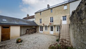 A stone building with a gravel courtyard, wooden door, and a small garden area. - Cyrano & Roxane - 1 km de la plage (Ver-sur-Mer)