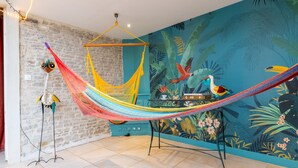 A room with a hammock, a mural, and a table with a bird sculpture. - Cyrano & Roxane - 1 km de la plage (Ver-sur-Mer)