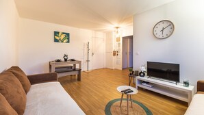 En moderne stue med sofa, fjernsyn og et ur på væggen.