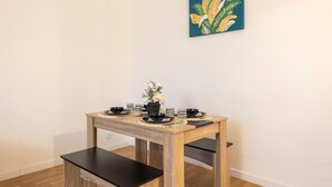 Et spisebord med en vase blomster, sort service og et billede på væggen.