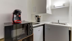 Eine kompakte Küche mit einer Bosch-Kaffeemaschine, einer Hisense-Mikrowelle, einem kleinen Kühlschrank und einem Spülbecken.
