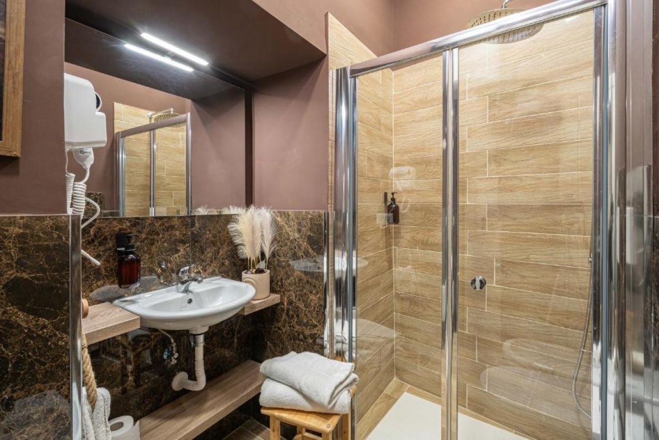 Ein modernes Badezimmer mit einer in Glas abgeschlossenen Dusche, einem мраморный Waschbecken und einem Waschtisch mit Spiegel.