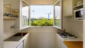 Una cocina compacta con ventana, un lavamanos, una estufa y un microondas.