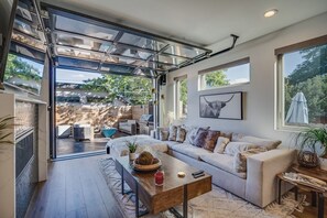 A modern living room with a glass door leading to an outdoor area, a sofa set, a coffee table, and a framed artwork on the wall. - Upscale Retreat LoHi 4Bd 5Ba | Gym Theatre Rooftop (Denver)