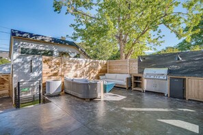 A modern outdoor living area with a barbecue grill, a sofa, and a stone fireplace. - Upscale Retreat LoHi 4Bd 5Ba | Gym Theatre Rooftop (Denver)