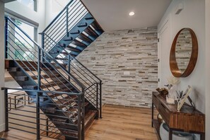 Un escalier moderne avec une rampe en métal, un mur en pierre et un plancher en bois.