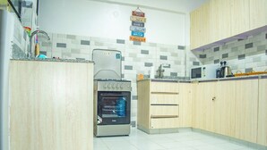 A kitchen with wooden cabinets, a stainless steel oven, and a tiled backsplash. - Spacious & Peaceful Getaway in Imara Daima (Nairobi)