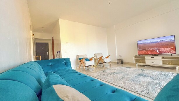 A living room with a blue sofa, a TV, and a small table. - Spacious & Peaceful Getaway in Imara Daima (Nairobi)