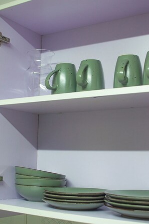 Una estantería con tazas y platos de cerámica verde.