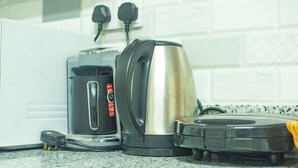 A kitchen with a coffee maker, a kettle, and a vacuum cleaner on the counter. - Spacious & Peaceful Getaway in Imara Daima (Nairobi)