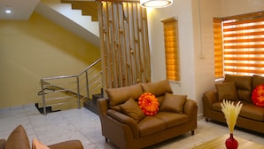 A modern living room with a brown sofa, a red vase, and a staircase. - 3 Bedrooms House in a secure and gated estate. (Lagos)
