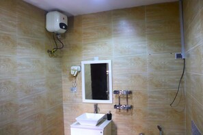 Un baño con lavamanos blanco, un espejo y un cabezal de ducha de mano.