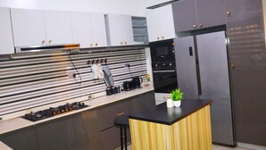 A modern kitchen with white cabinets, a black countertop, and stainless steel appliances. - 3 Bedrooms House in a secure and gated estate. (Lagos)