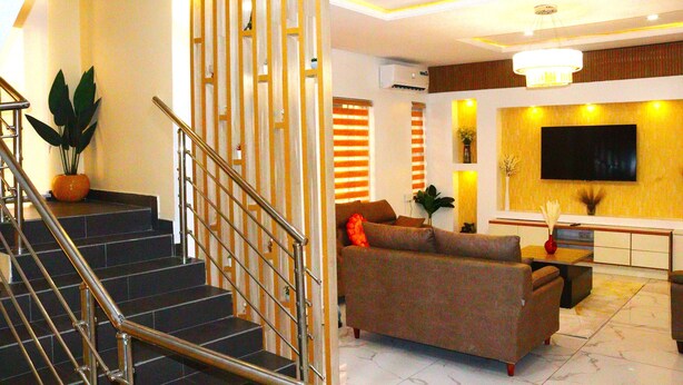 A modern living room with a staircase, a sofa, a TV, and a chandelier. - 3 Bedrooms House in a secure and gated estate. (Lagos)