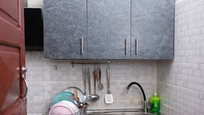 Une cuisine avec des meubles de couleur gris marbré, un évier en acier inoxydable et des ustensiles de cuisine suspendus.