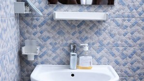 Une salle de bain avec un lavabo blanc, un distributeur de savon et un miroir au-dessus.