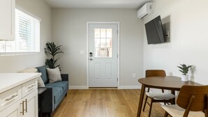 A compact living space with a kitchenette, a dining area, and a door leading to another room.