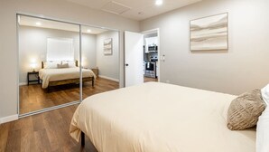 Une chambre avec un grand lit, un miroir et une vue sur la cuisine.